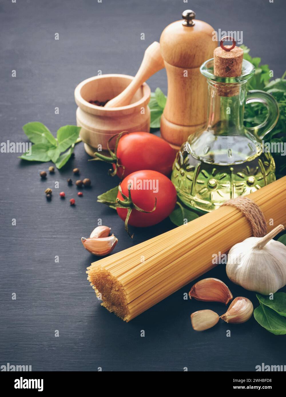Ingredients for cooking pasta spaghetti alla puttanesca - italian pasta dish with tomatoes, black olives, capers, anchovies and parsley. Stock Photo