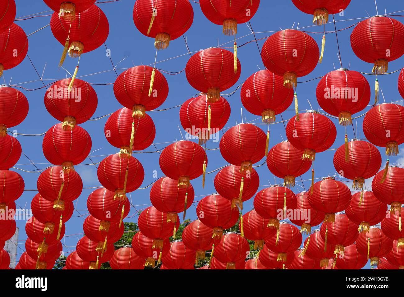 A collection of red paper lanterns hanging against a clear blue sky ...
