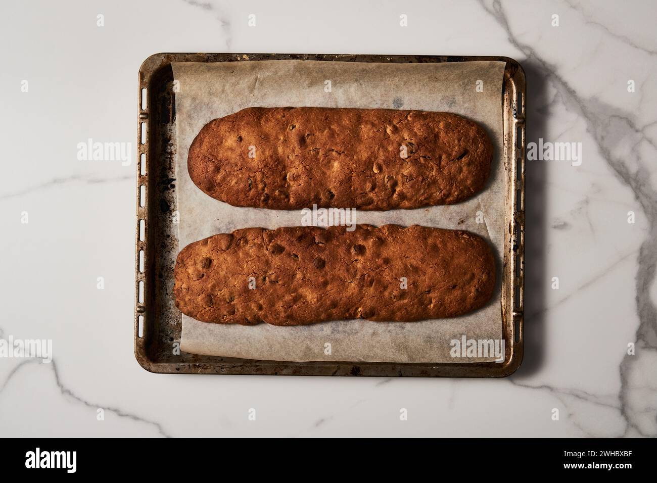 Freshly Baked Almond and Cranberry Biscotti on Parchment-Lined Baking Tray, Overhead Marble View Stock Photo