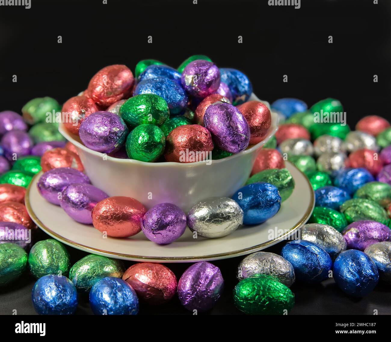 Overflowing bowl and plate of easter eggs on black Stock Photo