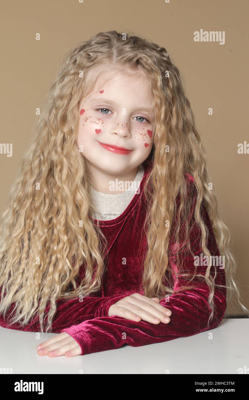 Portrait of cute little girl in red dress with long blonde hair and ...