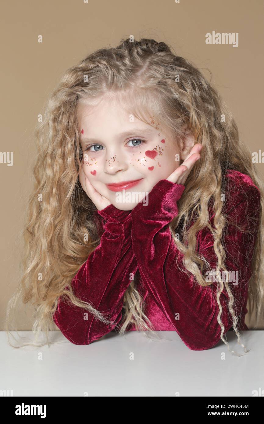 Portrait of cute little girl in red dress with long blonde hair and ...