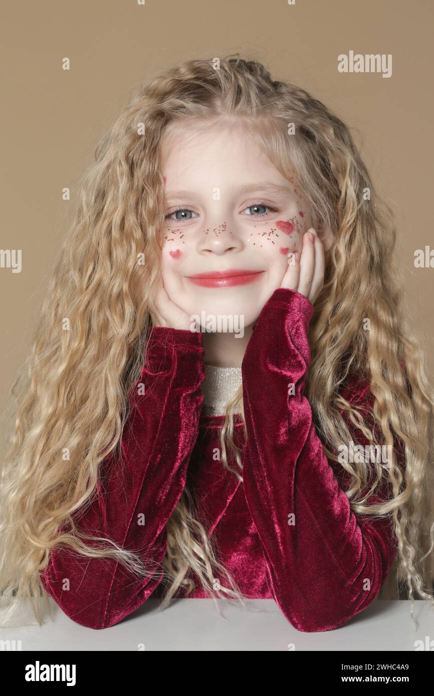 Portrait of cute little girl in red dress with long blonde hair and ...