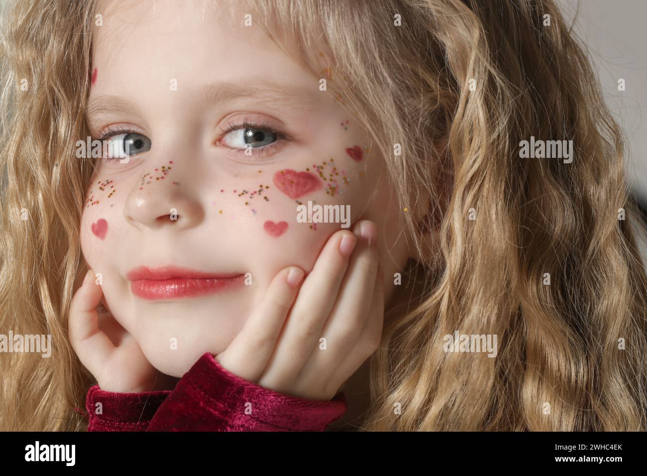 Portrait of cute little girl in red dress with long blonde hair and ...