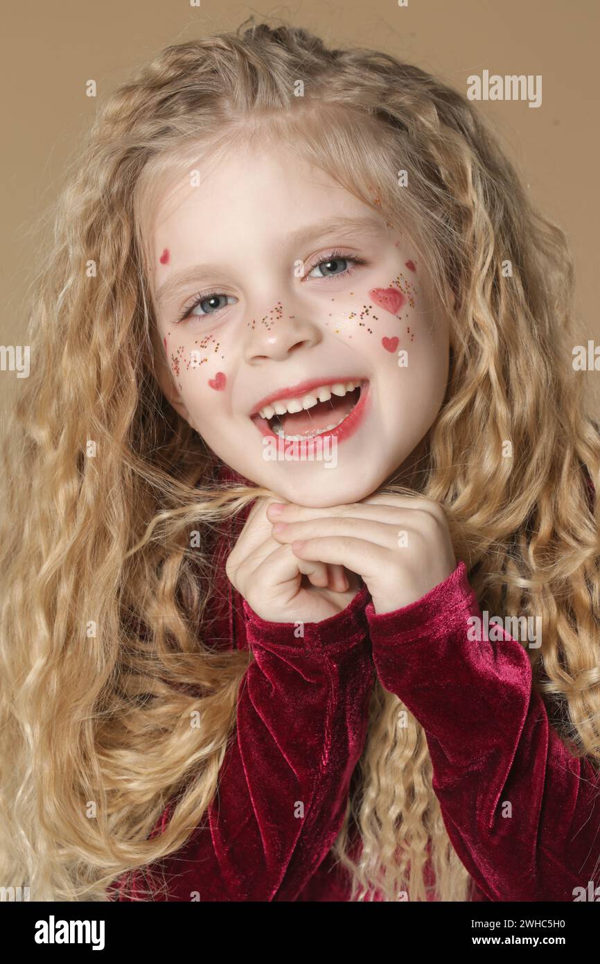 Portrait of cute little girl in red dress with long blonde hair and ...