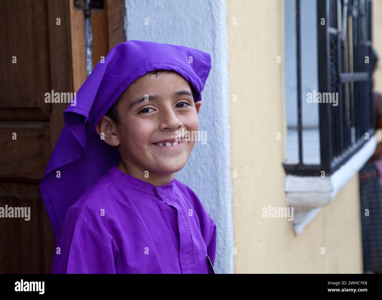 Antigua, Guatemala.  Young Boy, Dressed as a Cucurucho, Watching a Religious Procession during Holy Week, La Semana Santa Stock Photo