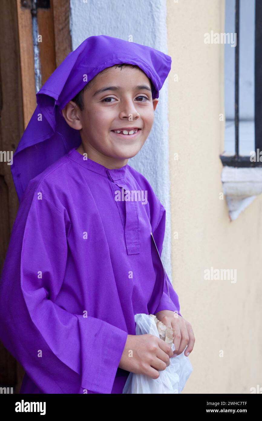 Antigua, Guatemala.  Young Boy, Dressed as a Cucurucho, Watching a Religious Procession during Holy Week, La Semana Santa Stock Photo
