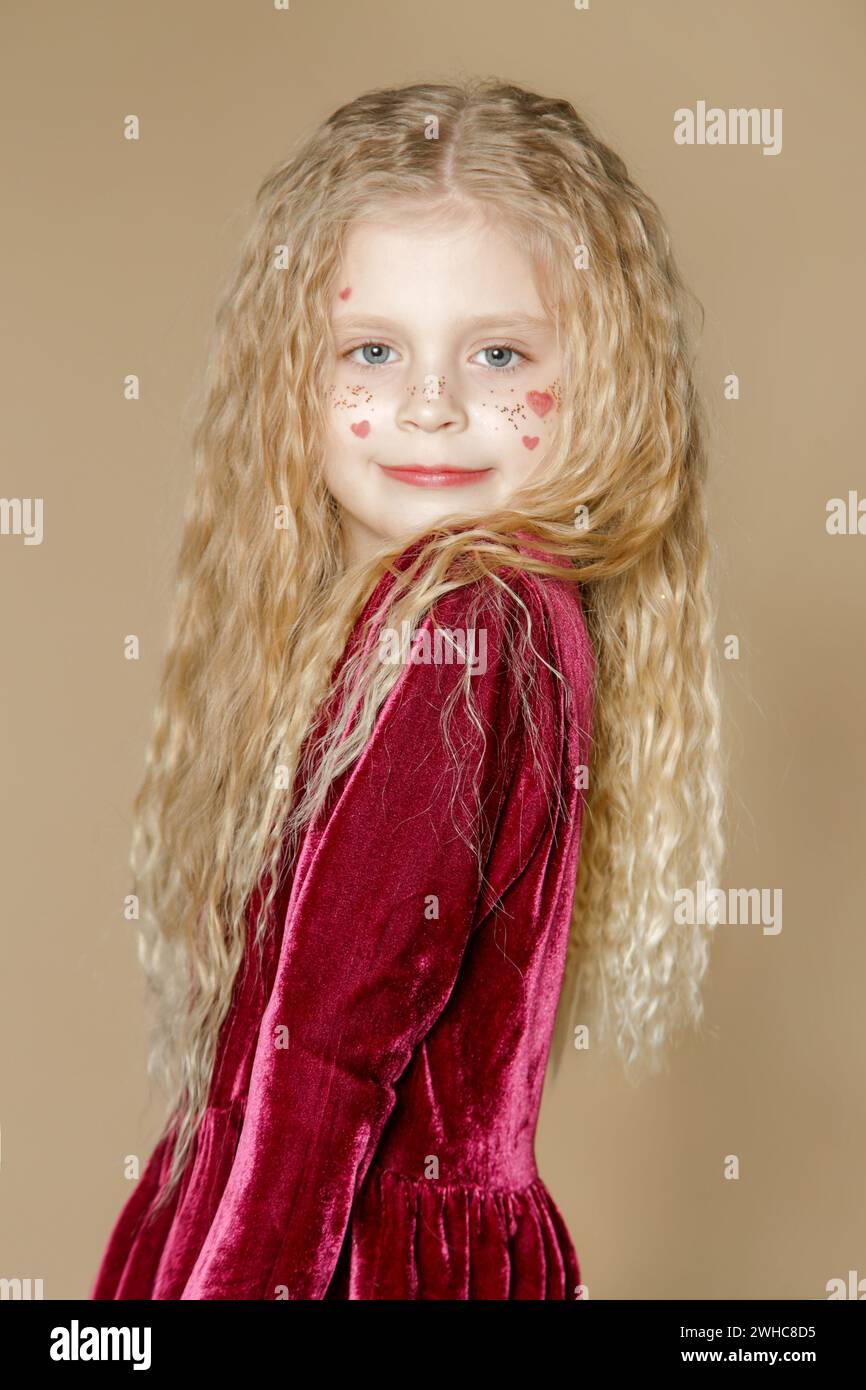 Portrait of cute little girl in red dress with long blonde hair and ...