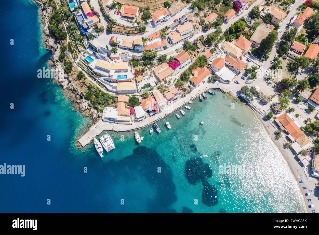 Assos picturesque fishing village from above, Kefalonia, Greece. Aerial drone view. Sailing boats moored in turquoise bay. Stock Photo