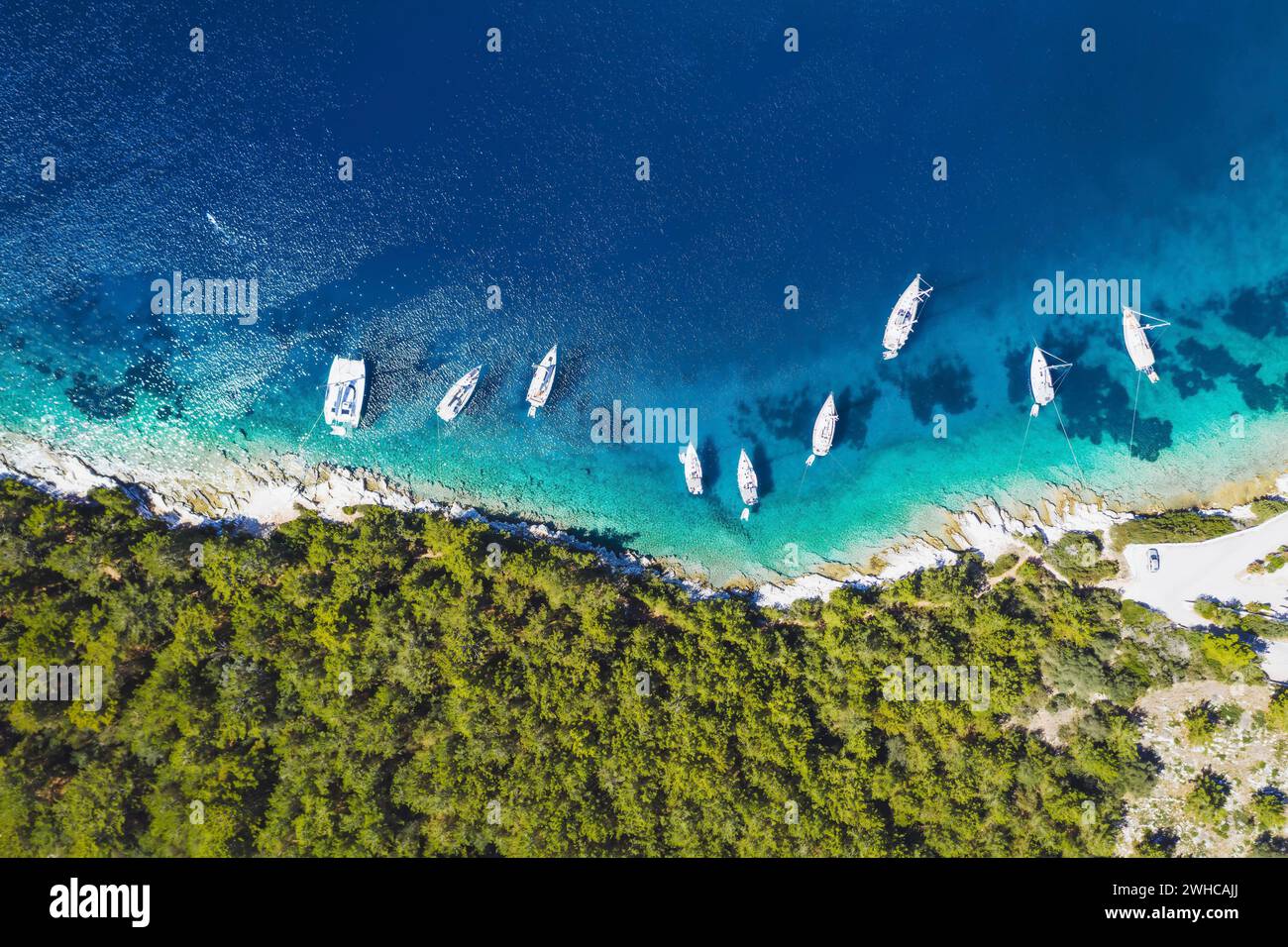 Top down aerial view of sailing boats docked in blue bay of Fiskardo, Kefalonia island, Ionian, Greece. Stock Photo