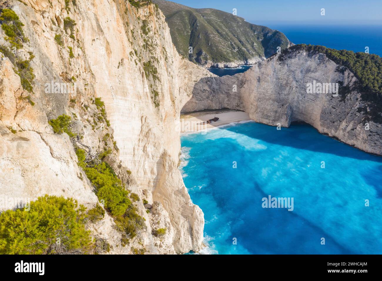 Aerial view of beautiful Navagio or Shipwreck beach on Zakynthos Island, Greece. Tourists on cliff edge enjoy view on summer travel trip. Stock Photo