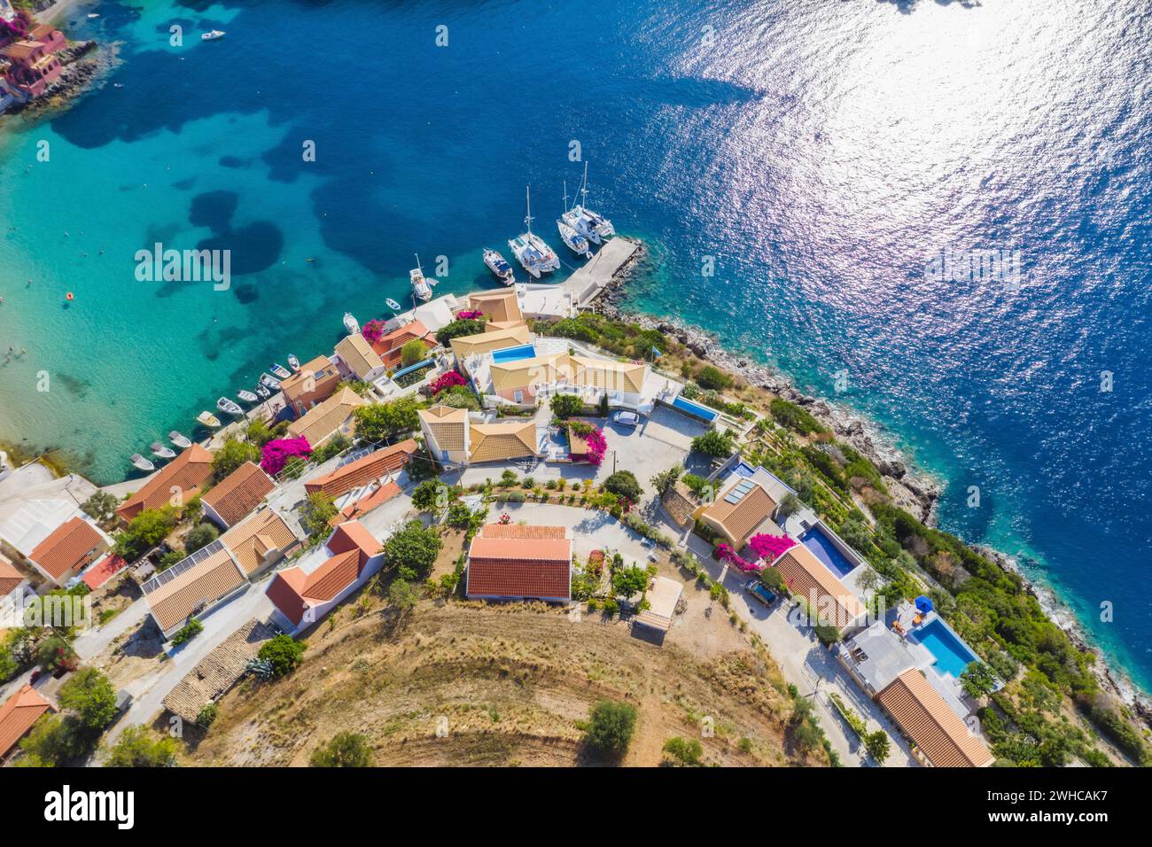 Assos picturesque fishing village from above, Kefalonia, Greece. Aerial drone view. Sailing boats moored in turquoise bay. Stock Photo