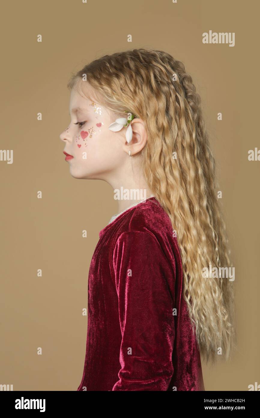 Portrait of cute little girl in red dress with long blonde hair and ...