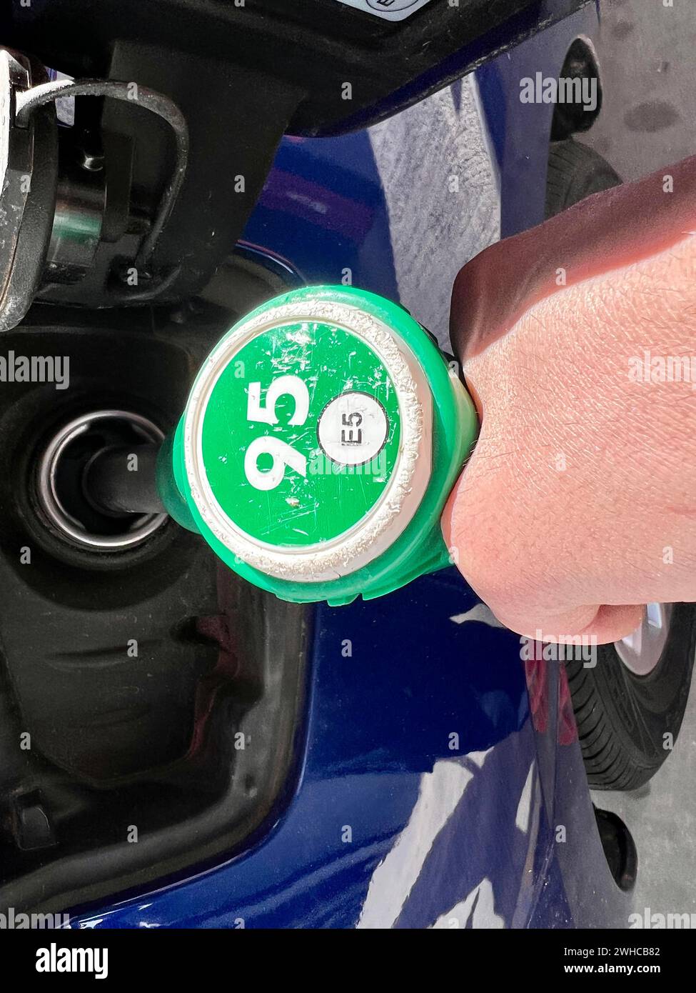 Detail of a person's hand pouring gas into a car at a gas station