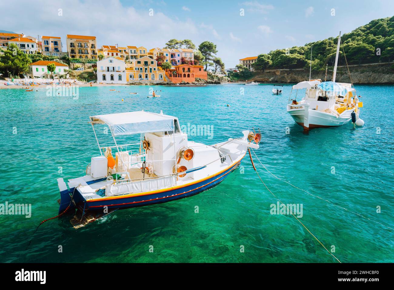 Assos village on Kefalonia island, Greece. White boats in the emerald rippled sea water bay. Stock Photo
