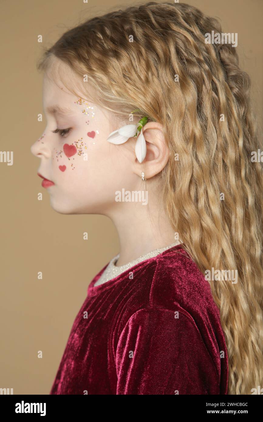 Portrait of cute little girl in red dress with long blonde hair and ...