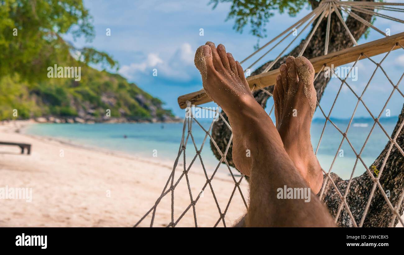 Men feet in Hammock, relaxing on the beach in Haad Rin, Ko Phangan. Thailand Stock Photo