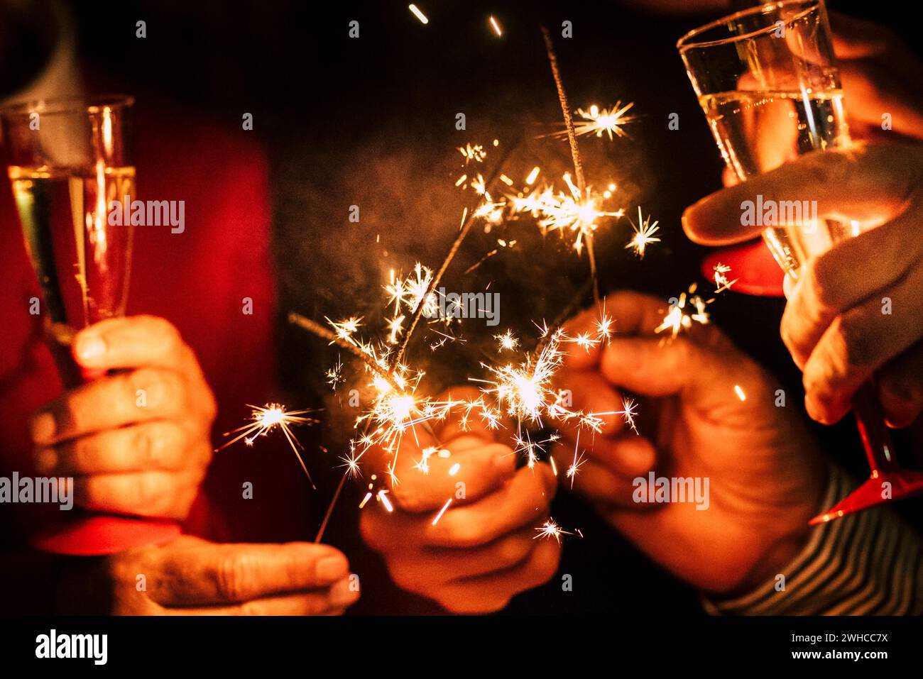 close up of sparklers and glass of champagne together celebrating the new year or the christmas day or another party together - people having fun Stock Photo