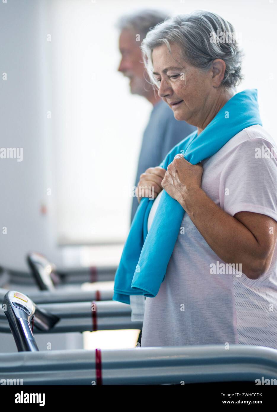 couple of two seniors and mature people training together at the gym - healthy and fitness lifestyle concept - walking in a tapirulan Stock Photo