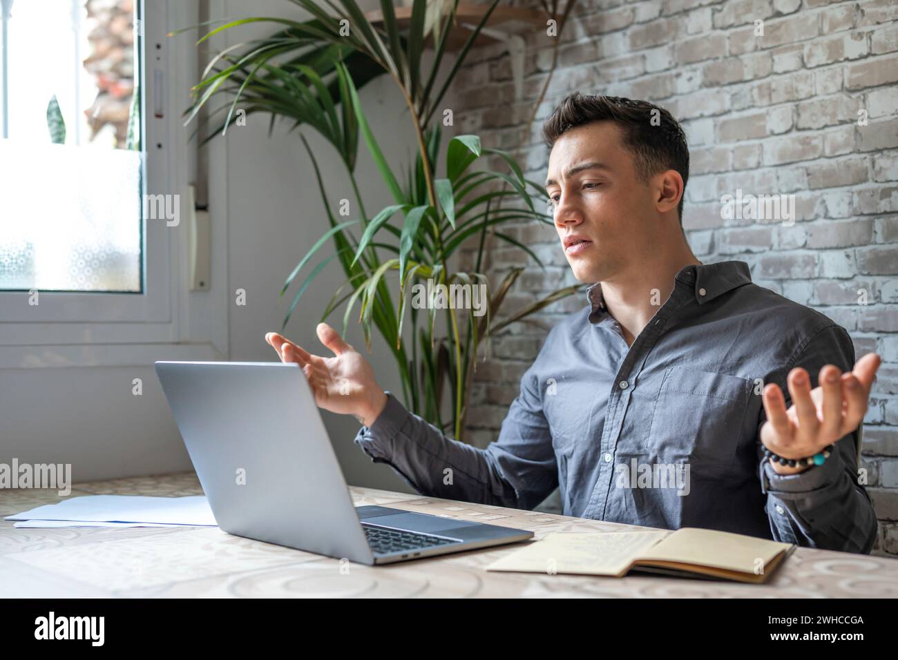 Unhappy young caucasian male worker in glasses look at laptop screen shocked by gadget breakdown or operational problems. Frustrated man confused surprised by unexpected error on computer device. Stock Photo