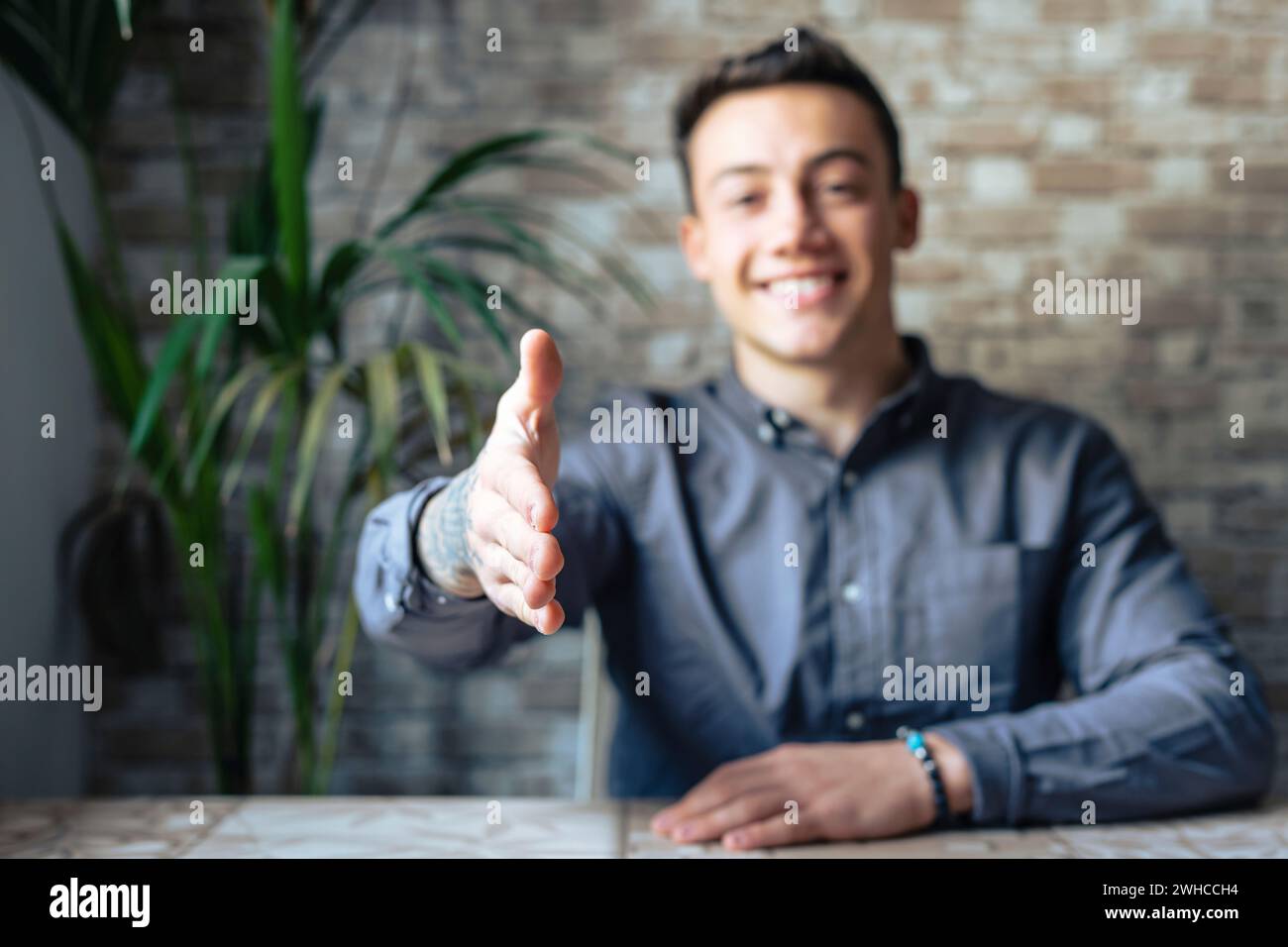 Portrait of happy young male hr stretching hand inviting you spectator to join corporate team, friendly capable manager looking at camera extending hand for handshake welcoming new client or colleague Stock Photo