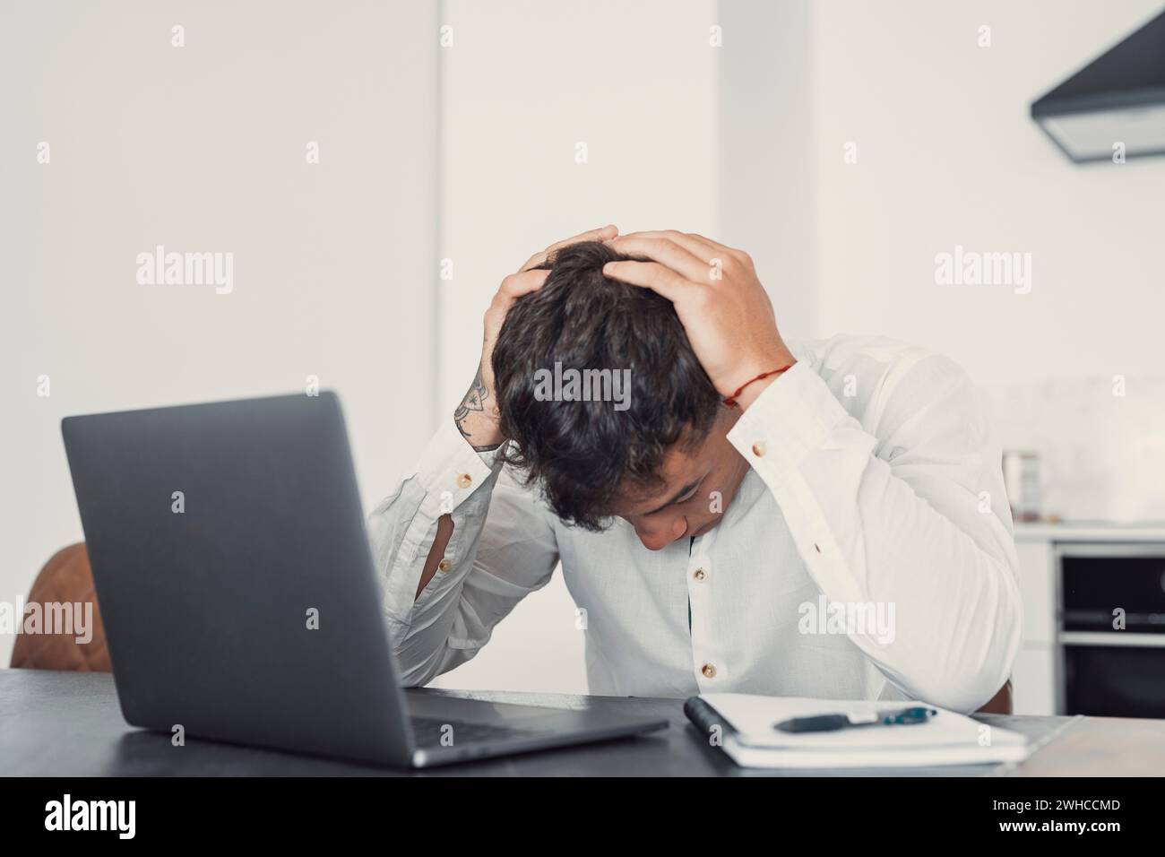 Unhappy young Caucasian male worker in glasses look at laptop screen shocked by gadget breakdown or operational problems. Frustrated man confused surprised by unexpected error on computer device. Stock Photo