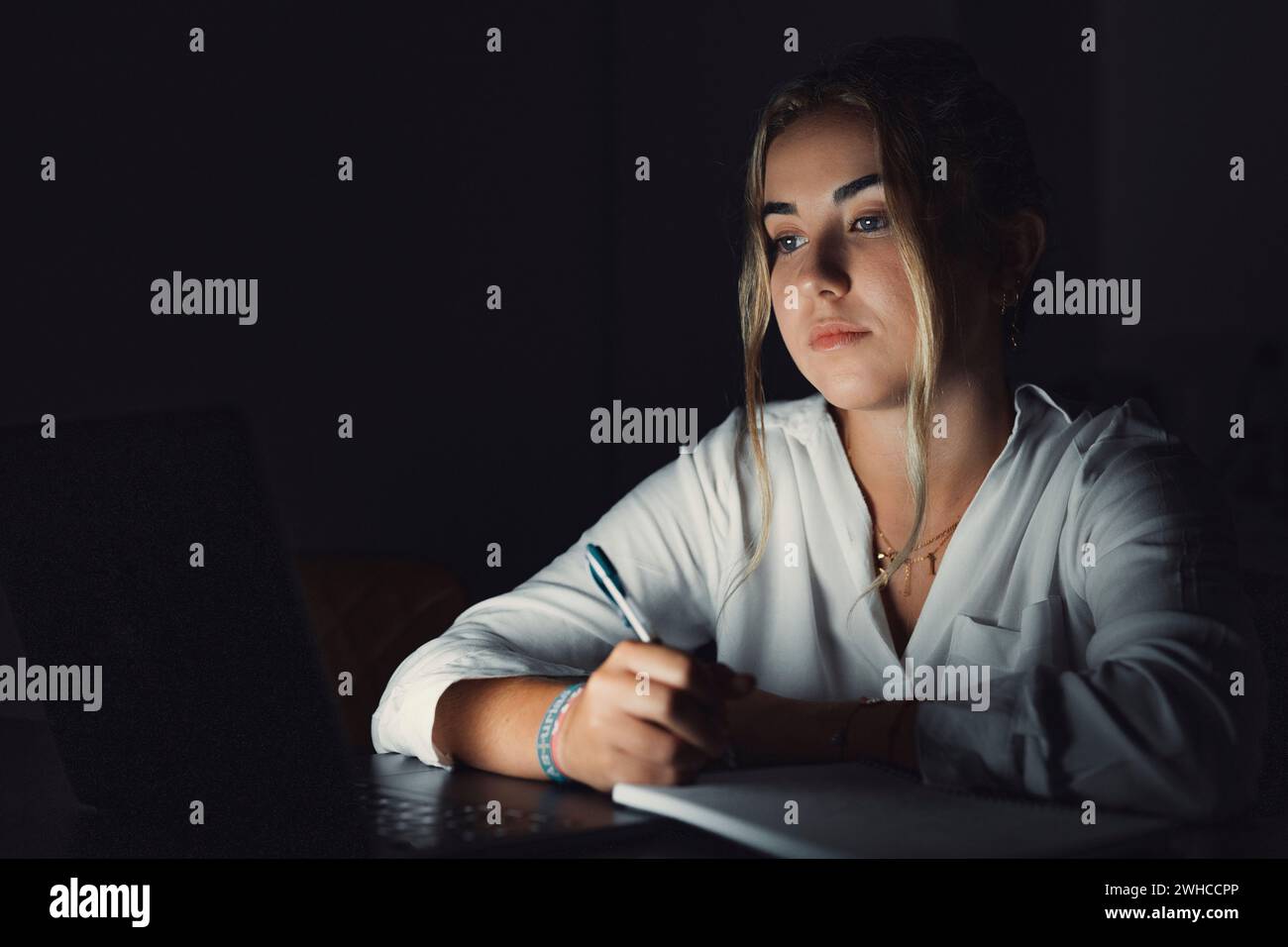 Exhausted upset young woman sit at office desk after end of workday alone massage temples trying to remember important information. Stressed tired female employee feel headache caused by work overtime Stock Photo