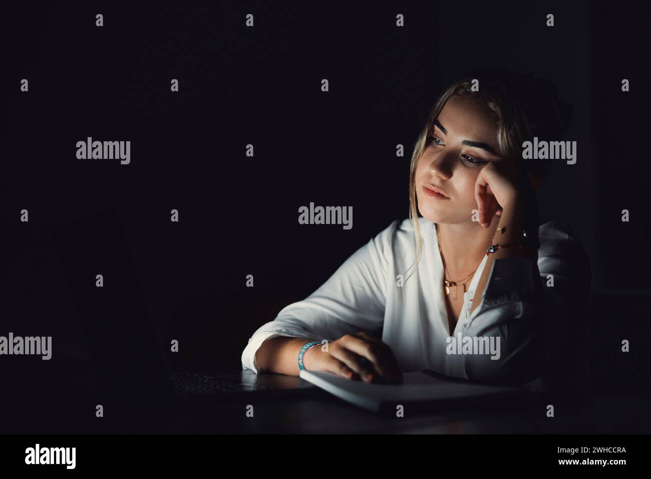 Exhausted upset young woman sit at office desk after end of workday alone massage temples trying to remember important information. Stressed tired female employee feel headache caused by work overtime Stock Photo