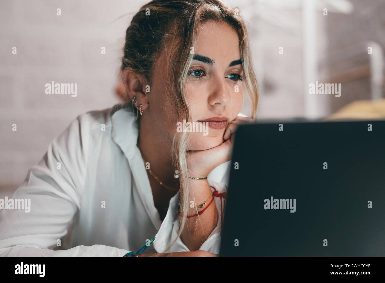 Close up of one young pretty woman using laptop indoor at home lying on the bed surfing the net. Millennial teenager having fun online studying. Stock Photo
