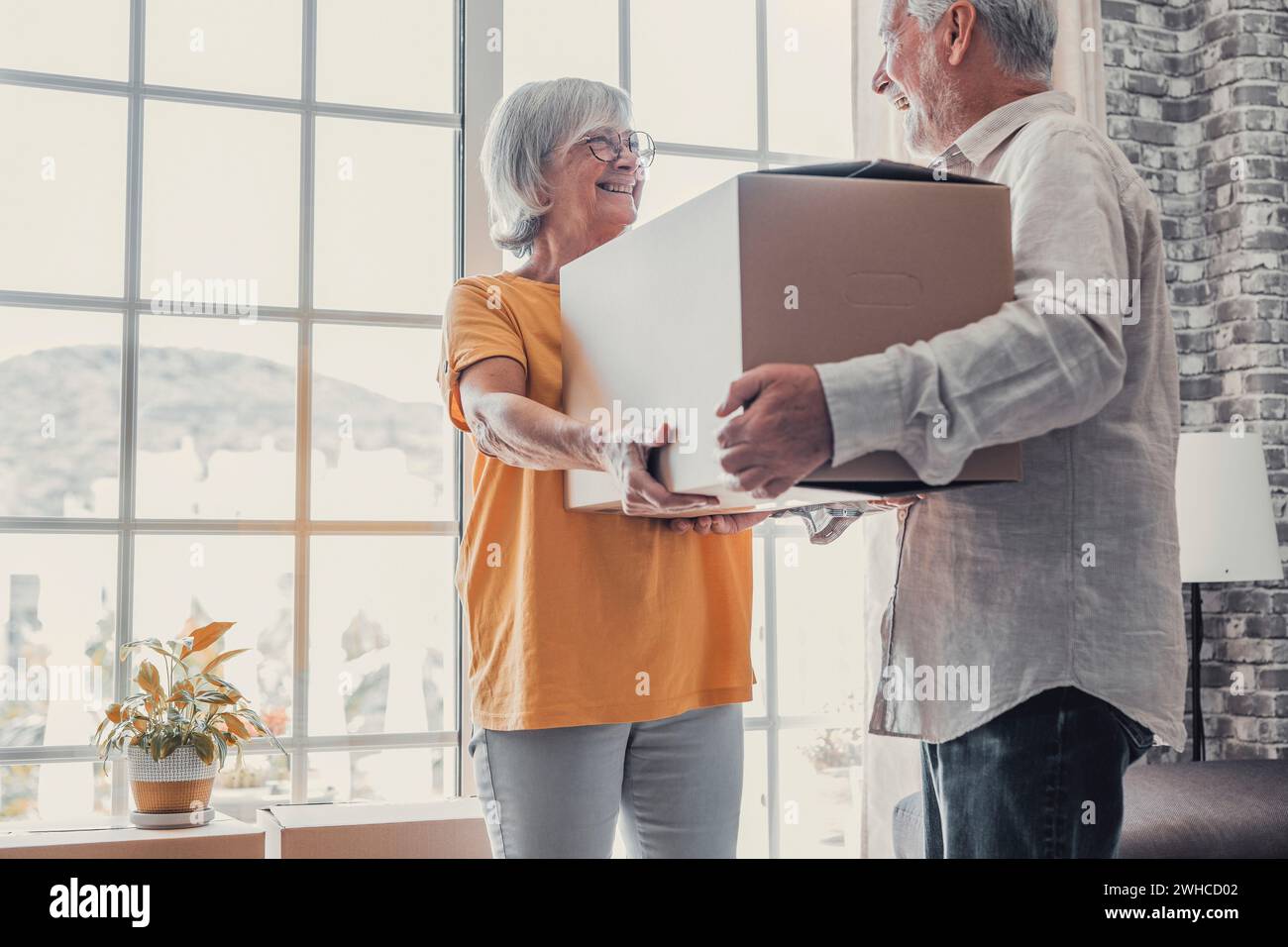 Mature couple moving into new apartment, carrying cardboard boxes into