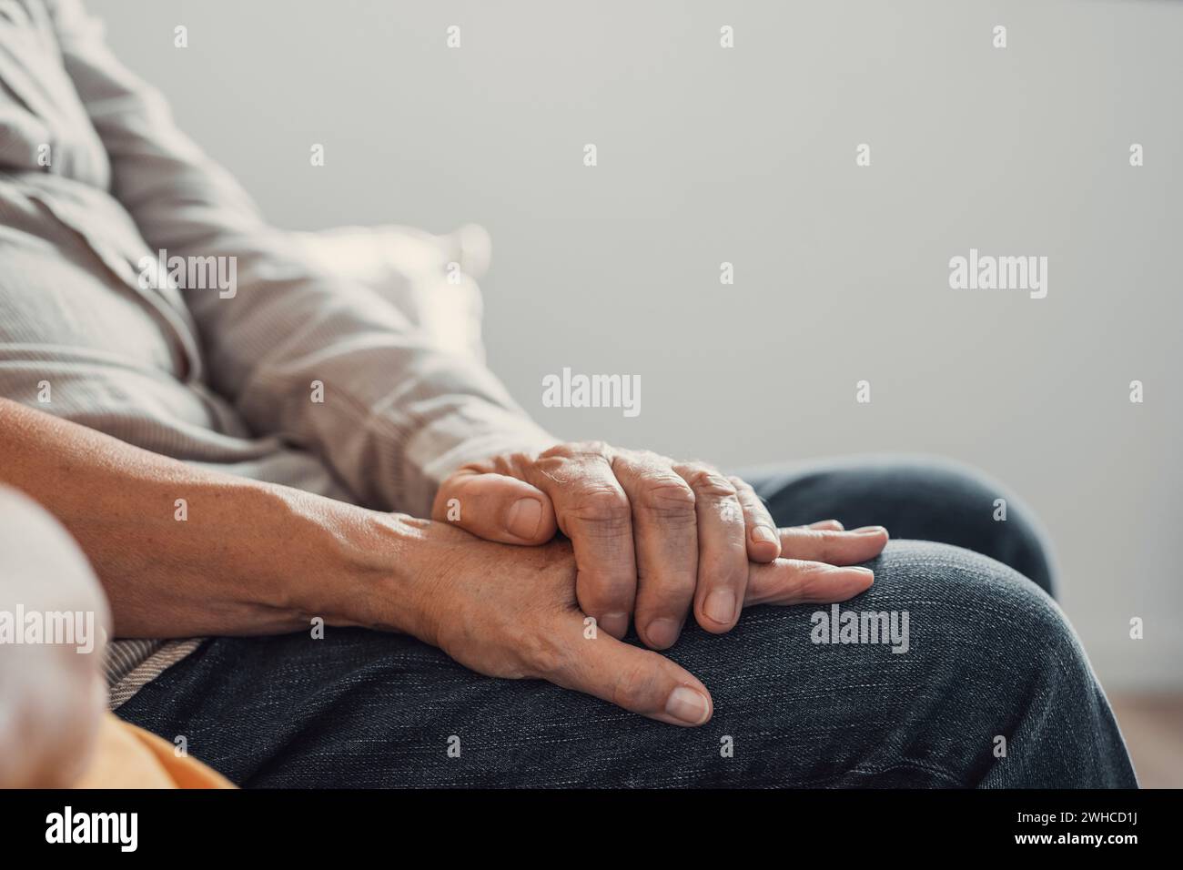 Close up elderly affectionate woman covering wrinkled hands of mature husband, showing love and support at home. Caring middle aged family couple enjoying sincere trustful honest conversation. Stock Photo
