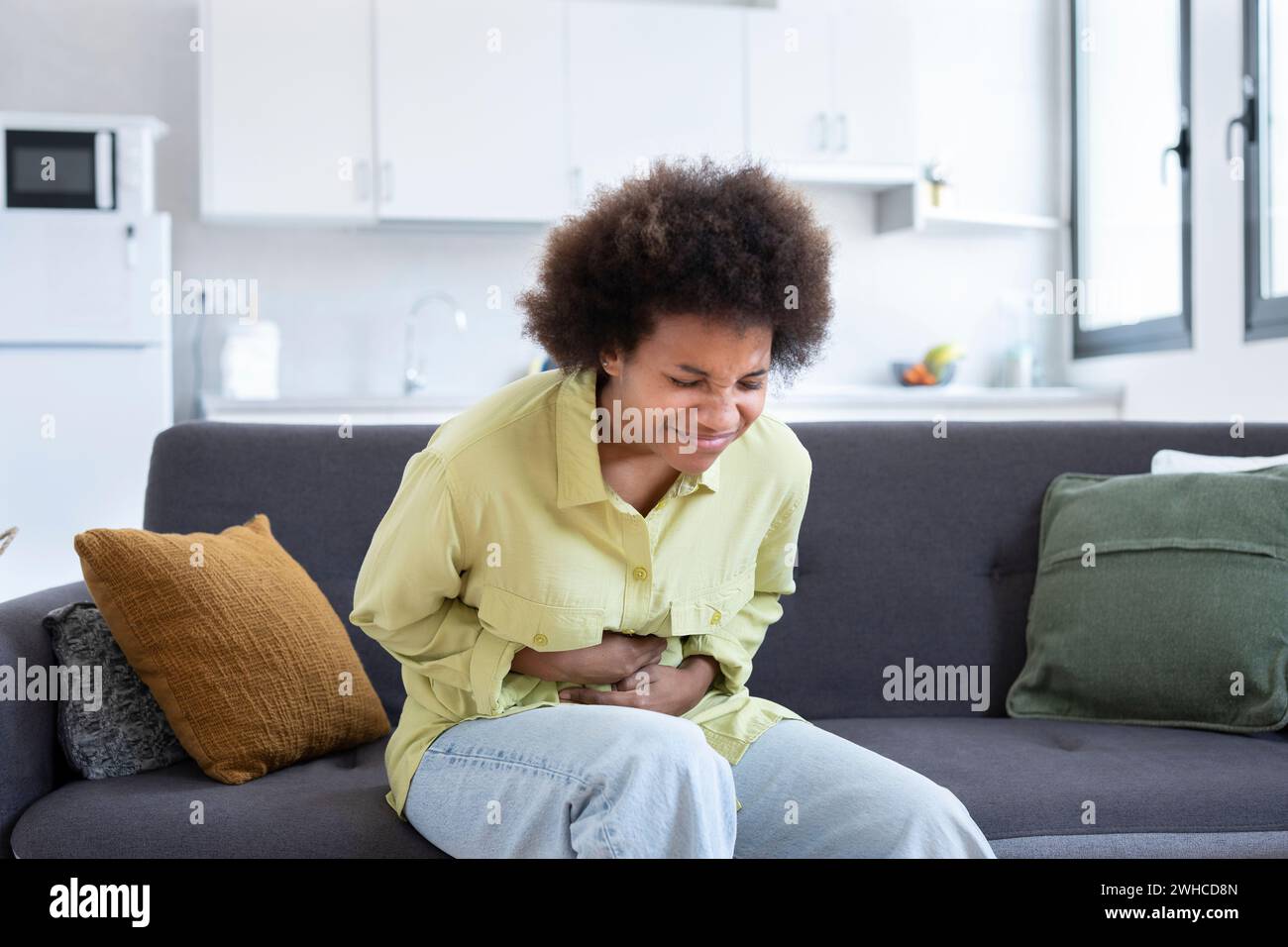 Sick young woman in pain holding belly stomach feeling hurt abdomen ache gastritis pancreatitis symptoms or diarrhea, upset teen girl suffering from indigestion flatulence abdominal problem concept Stock Photo