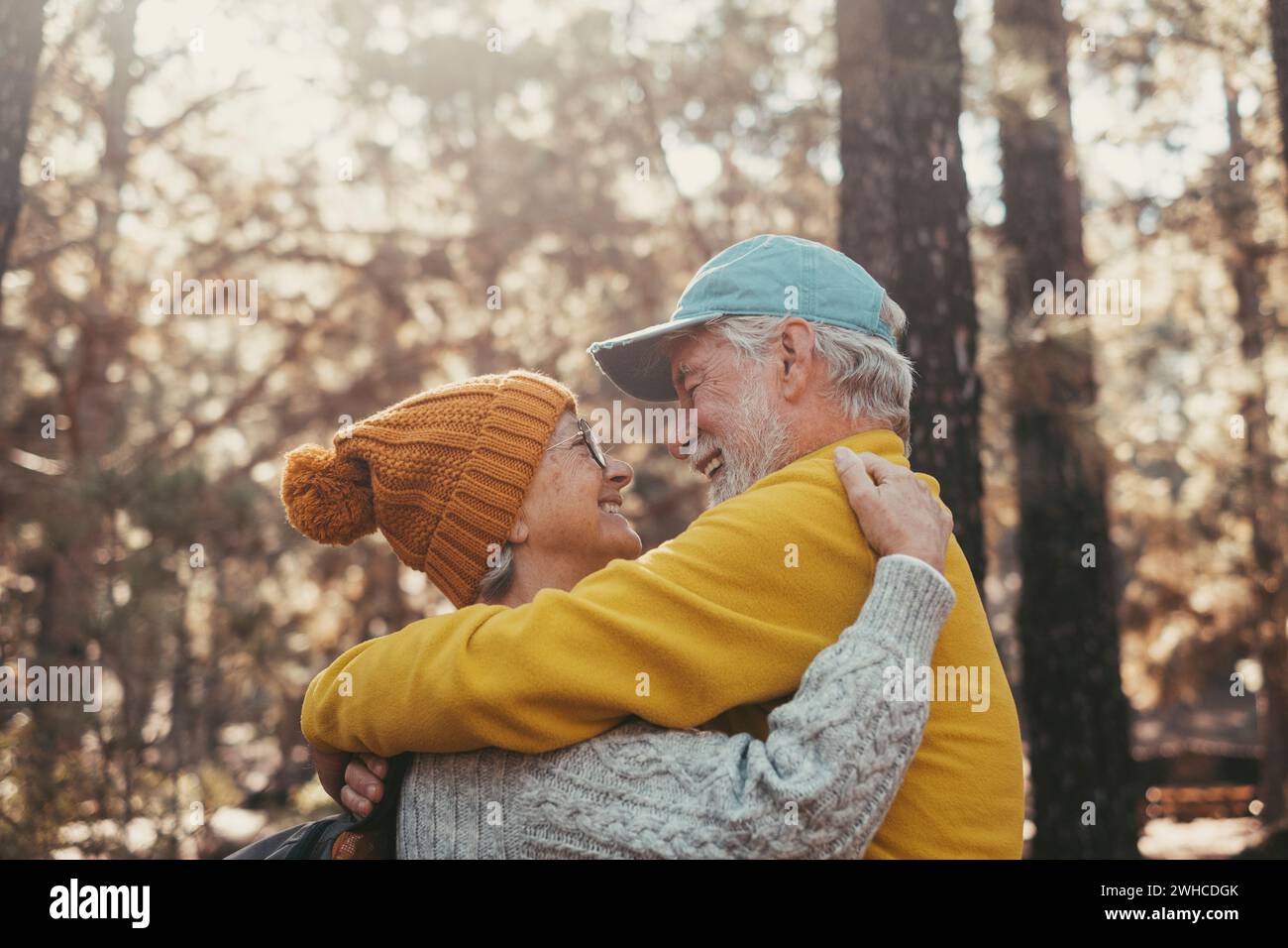 Portrait, close up of old people smiling and enjoying looking each other in the forest of mountain. Cute couple of mature seniors in love feeling happy and taking care. Stock Photo