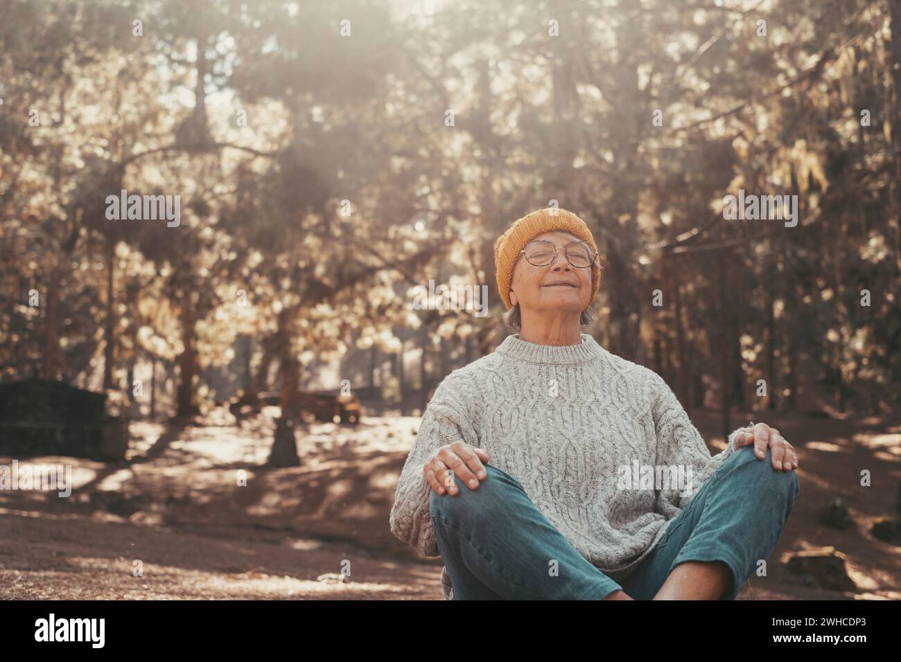 Portrait, close up of one middle age old woman resting and relaxing doing yoga in the forest of mountain in the nature. One mature female person enjoying having fun lifestyle. Stock Photo