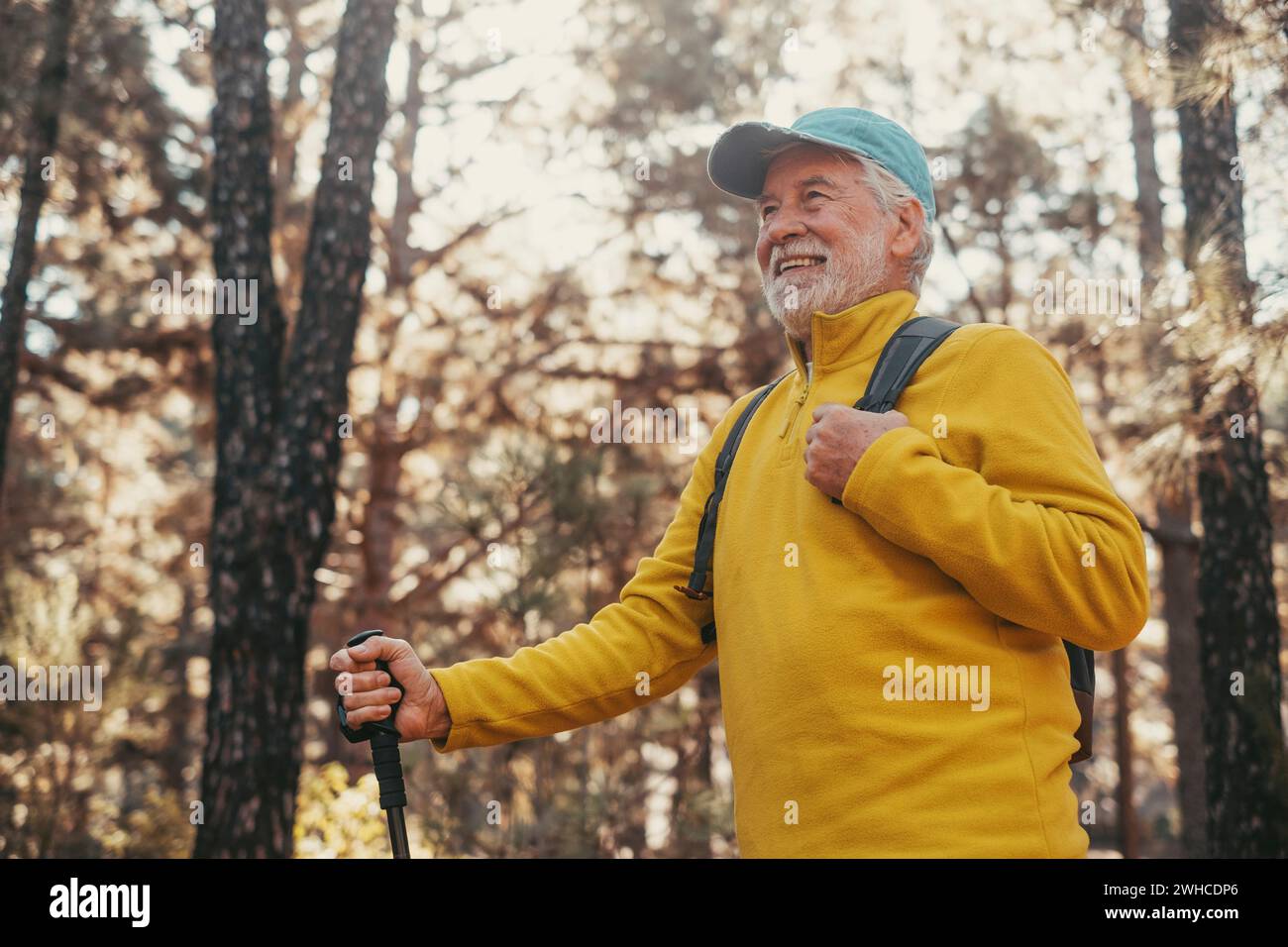 Portrait, close up of middle age caucasian man walking and enjoying nature in the middle of trees in forest. Old mature male wearing glasses trekking and discovering. Stock Photo