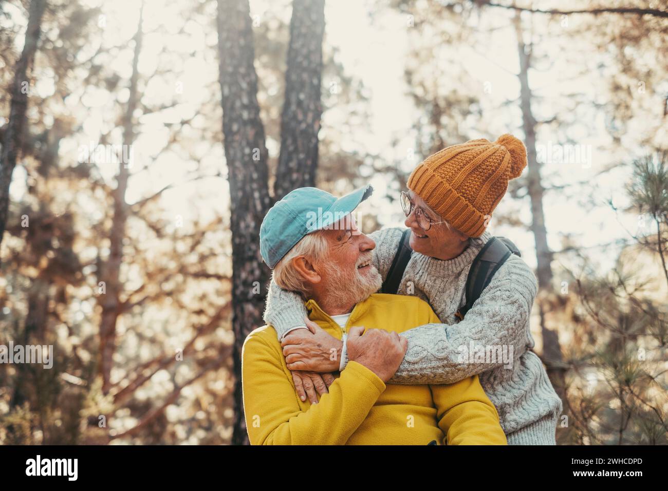 Portrait, close up of old people smiling and enjoying looking each other in the forest of mountain. Cute couple of mature seniors in love feeling happy and taking care. Stock Photo
