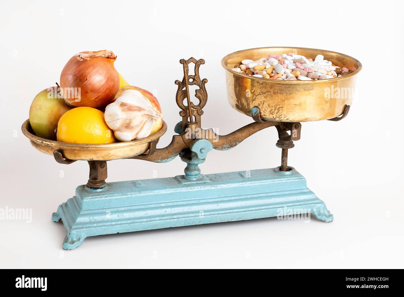 Kitchen scales with onions, garlic and fruit next to pills, white background Stock Photo
