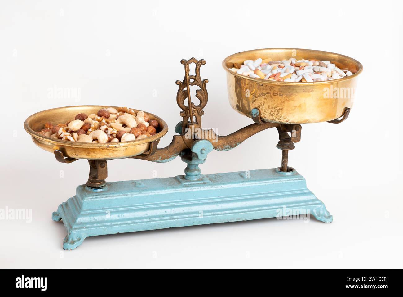 Nuts on one side of an antique scale and medication on the other, white ...