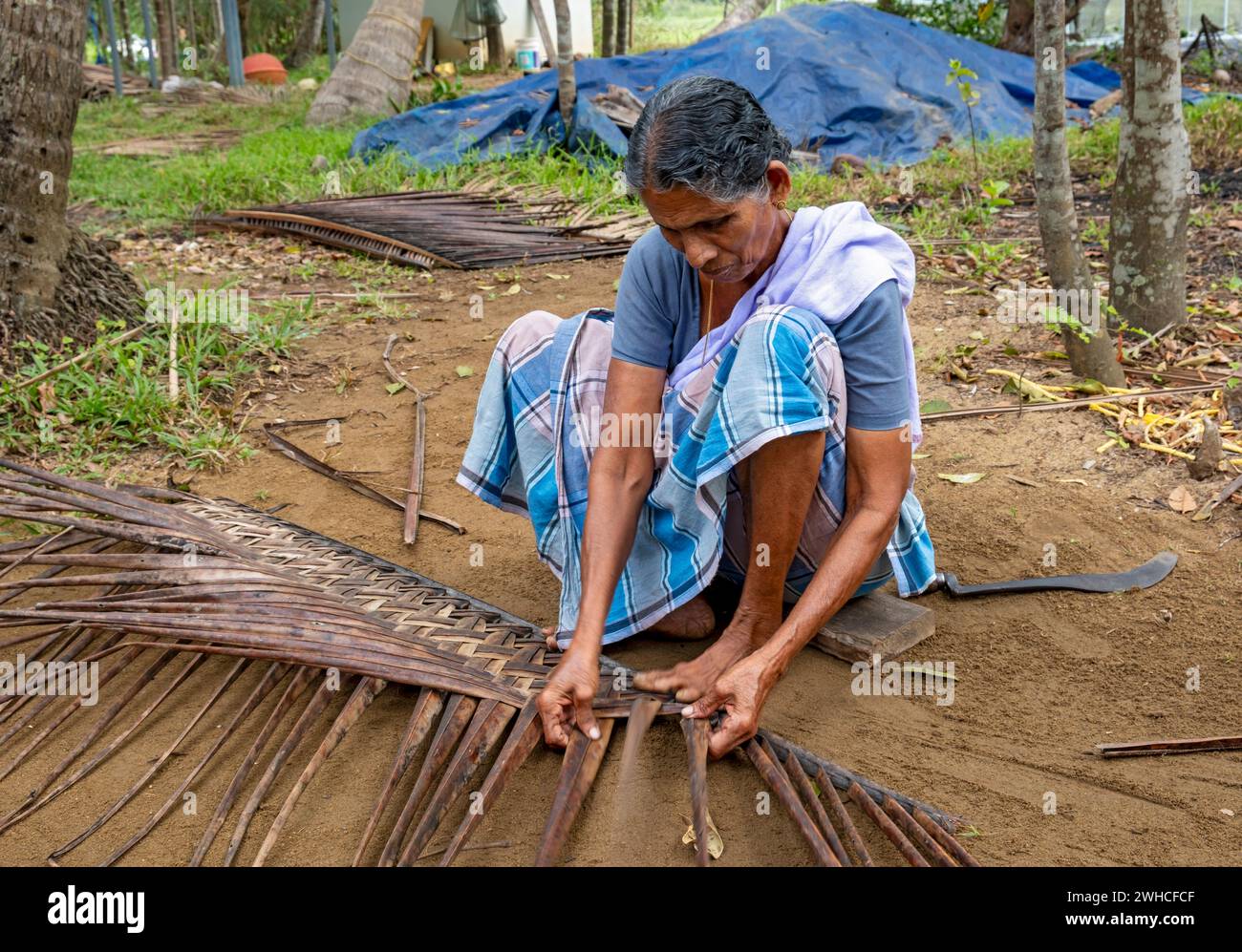 A village woman demonstrates the traditional craft of making mats from
