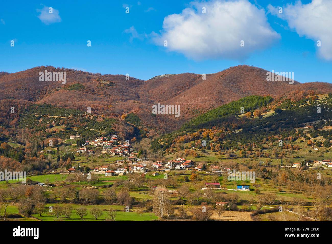 View of a village surrounded by autumnal hills and meadows, Erymanthos Mountains, northwest of the Peloponnese peninsula, Peloponnese, Greece Stock Photo