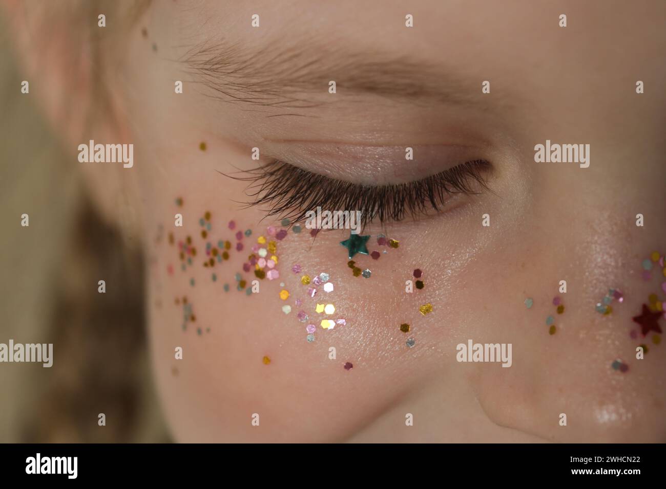 Close up of girl's closed eye with long lashes and glitters around Stock Photo