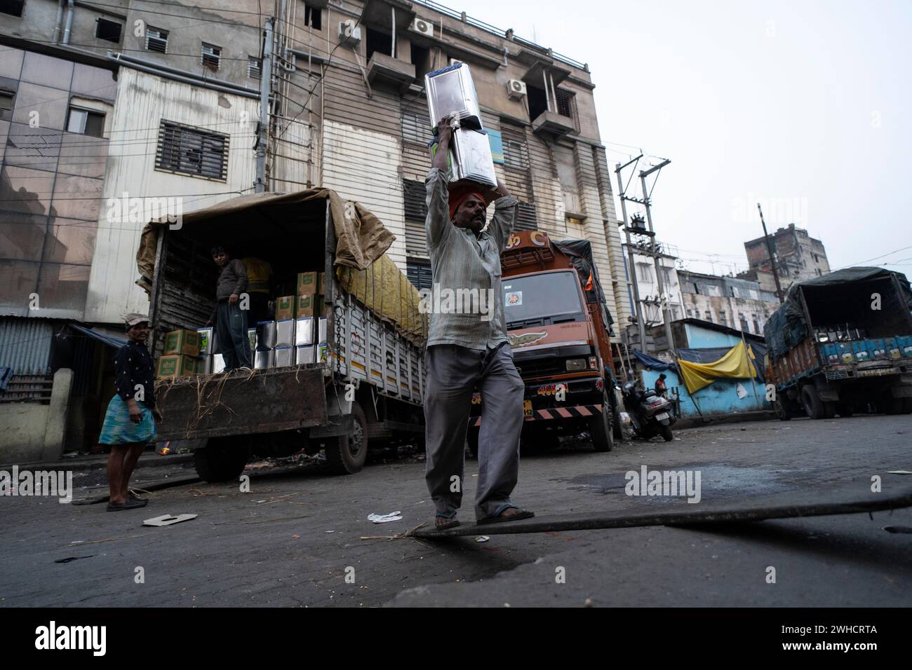 Labourer carries good from truck at a wholesale market, ahead of the