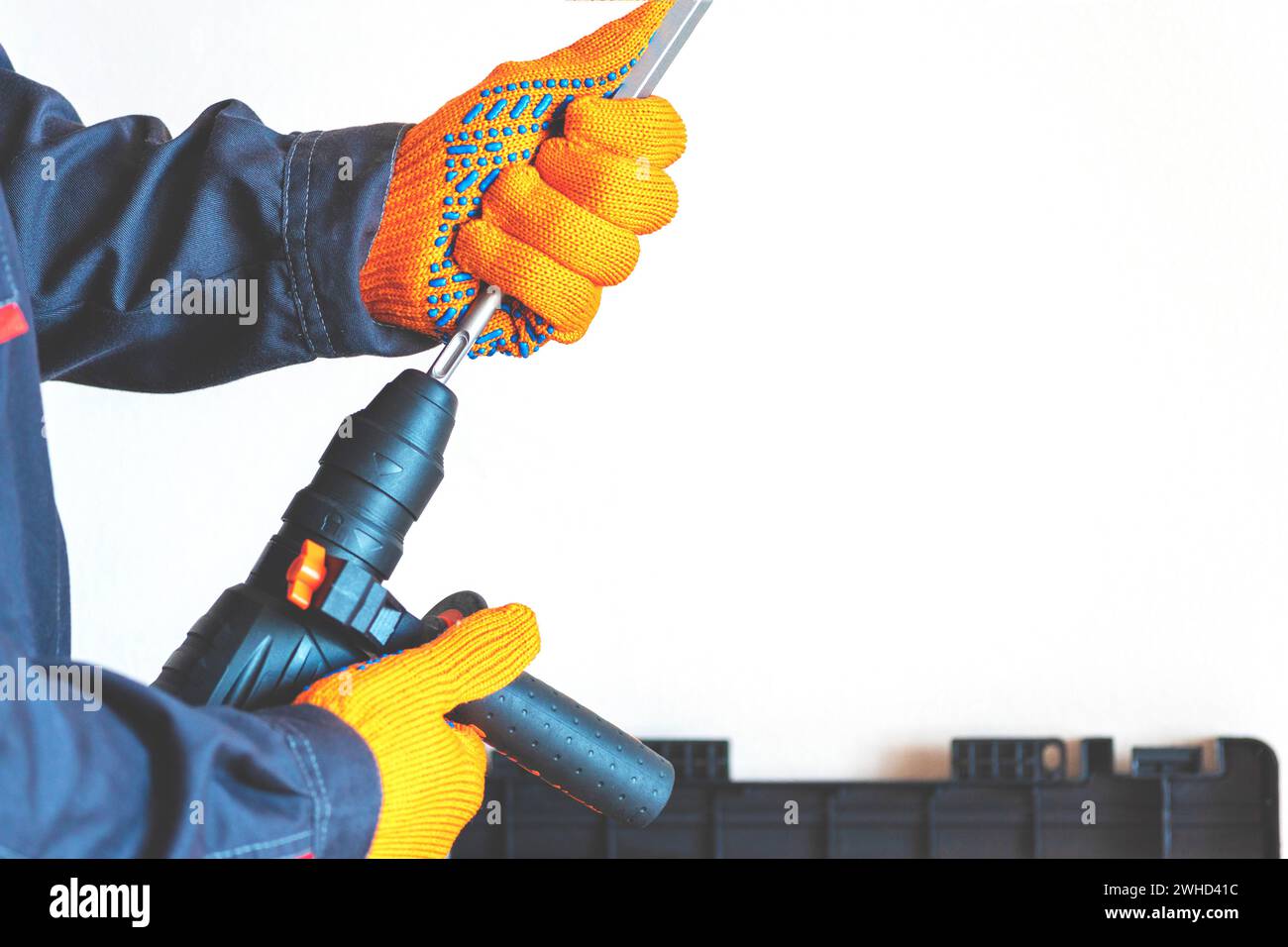 close-up. hands in protective gloves, hammer drill, installation of a chisel in a perforator. The concept of replacing the rotary drill. Stock Photo