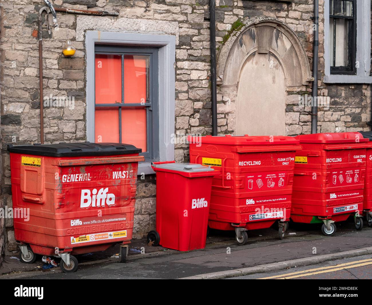 Red 'Biffa' bins for recycling and disposing of trade waste sit on the pavement outside a local business. Stock Photo