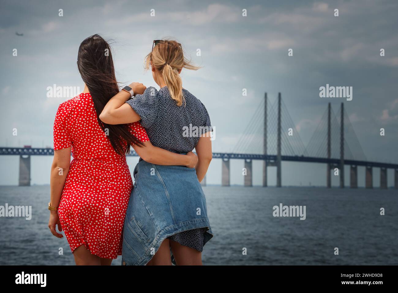 Two Friends Share an Embrace by the Oresund Bridge, DenmarkSweden. Stock Photo