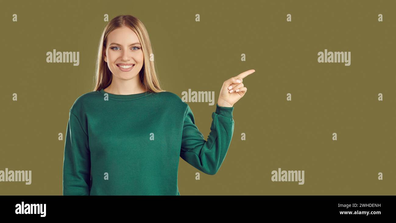 Portrait of young woman pointing her finger to side Stock Photo