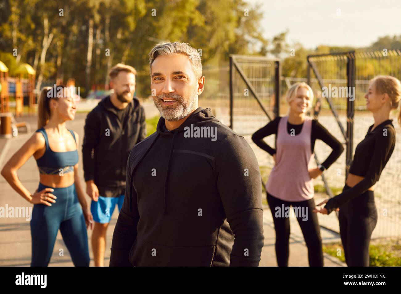 Portrait of smiling mature sporty man looking at camera after fit exercises in nature in the park. Stock Photo