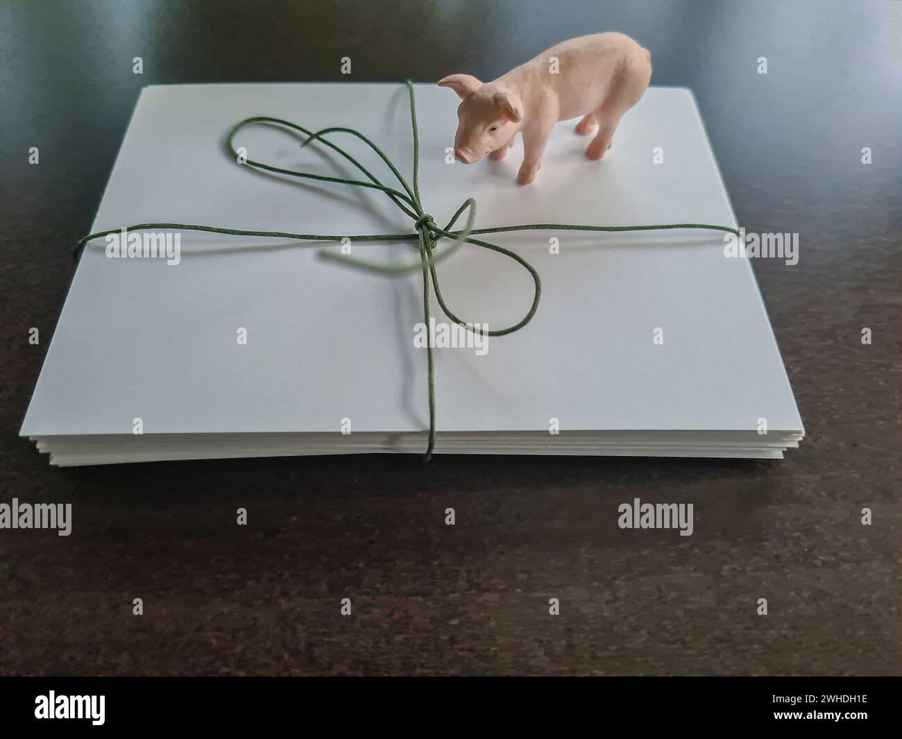 One gift is decorated with white wrapping paper and green ribbon and packing tape with a small pink toy pig Stock Photo