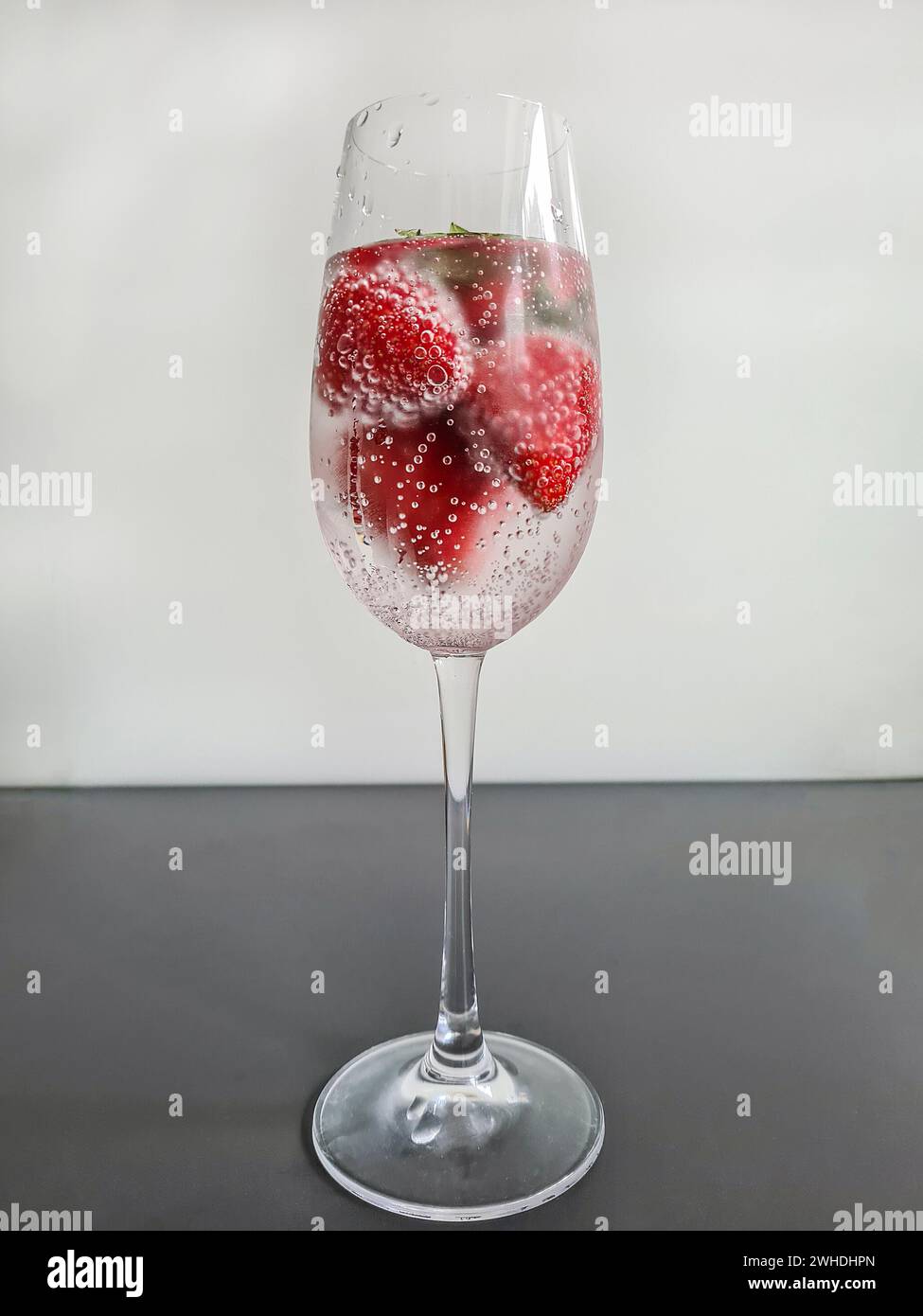 Fresh red whole ripe strawberries with mineral water in a champagne glass as a non-alcoholic refreshing drink in summer Stock Photo