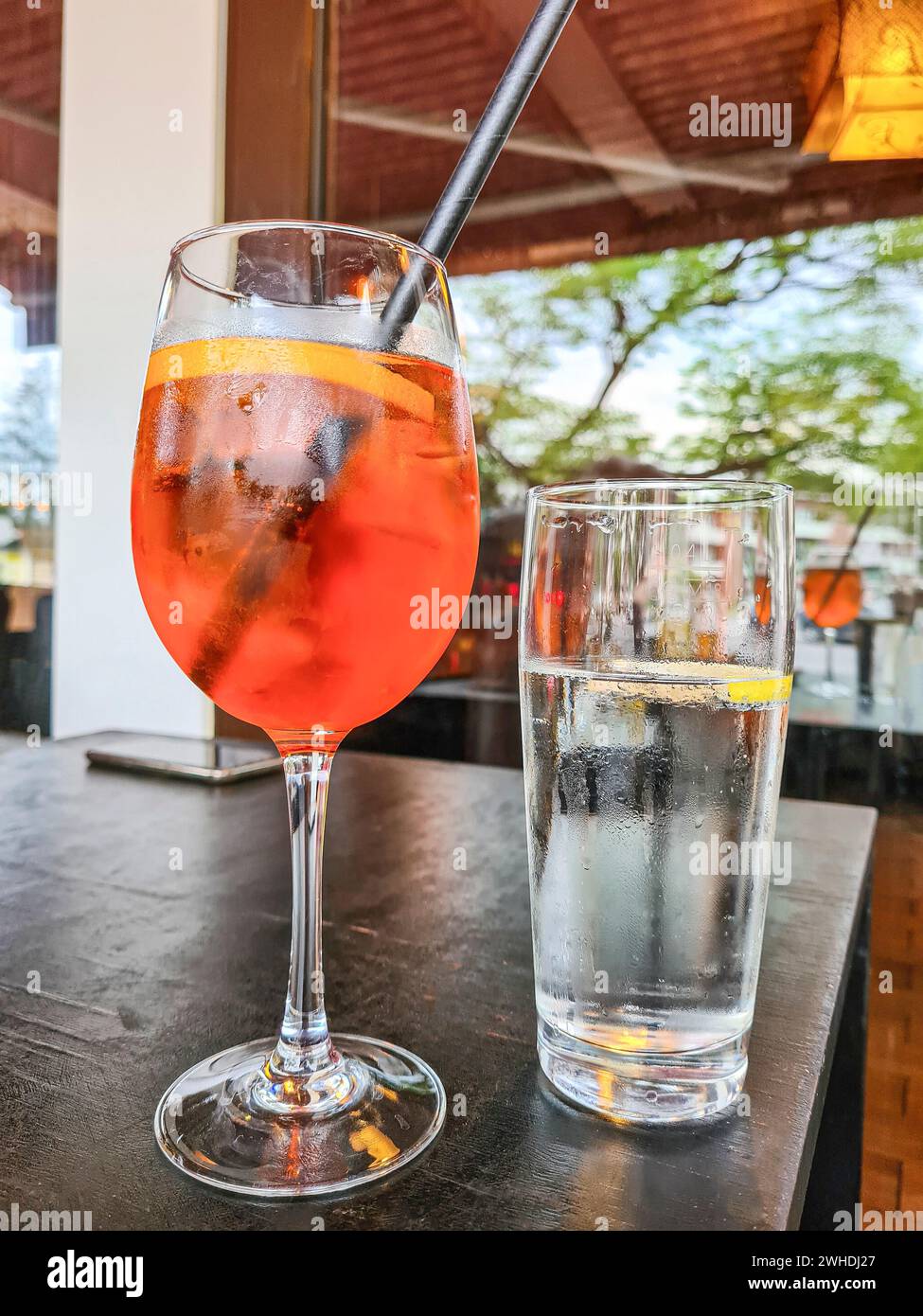 The alcoholic soft drink Aperol Spritz is placed on a table next to a glass of mineral water Stock Photo